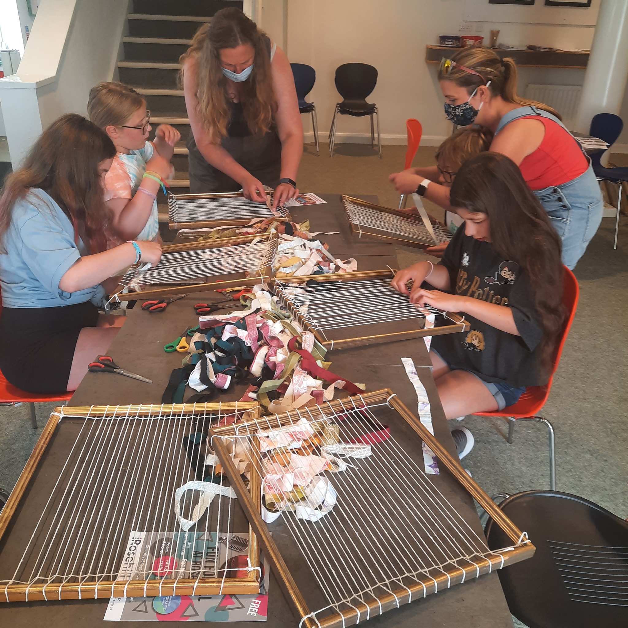 Families weaving broad stripes of fabric into looms