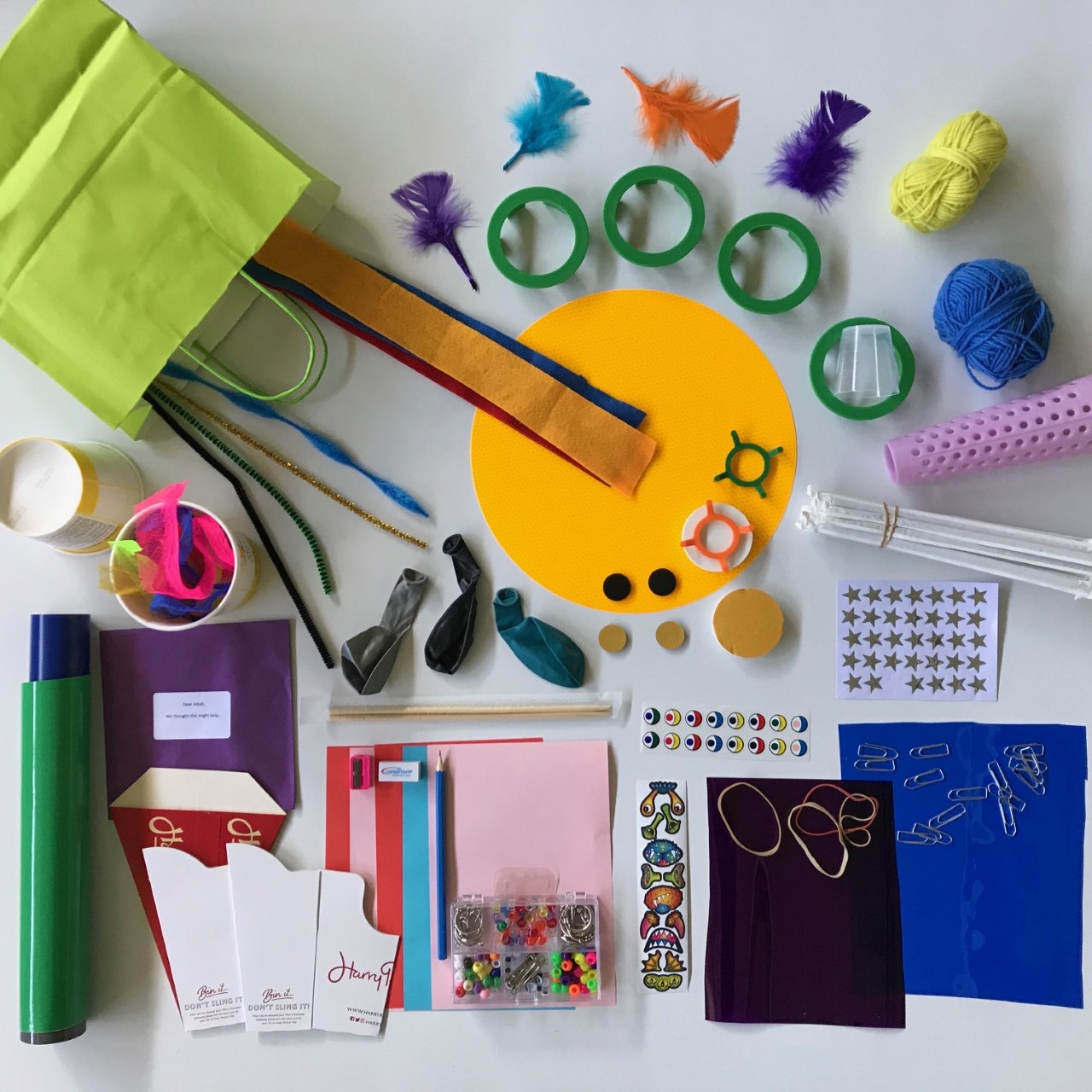 Various arts and crafts resources including cardboard, stickers and feathers spread out on a table