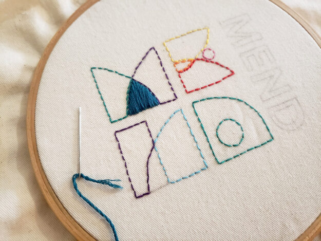 The word MEND embroidered with yarn of various colours