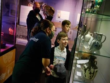 Families and museum staff looking at vases exhibited in a museum