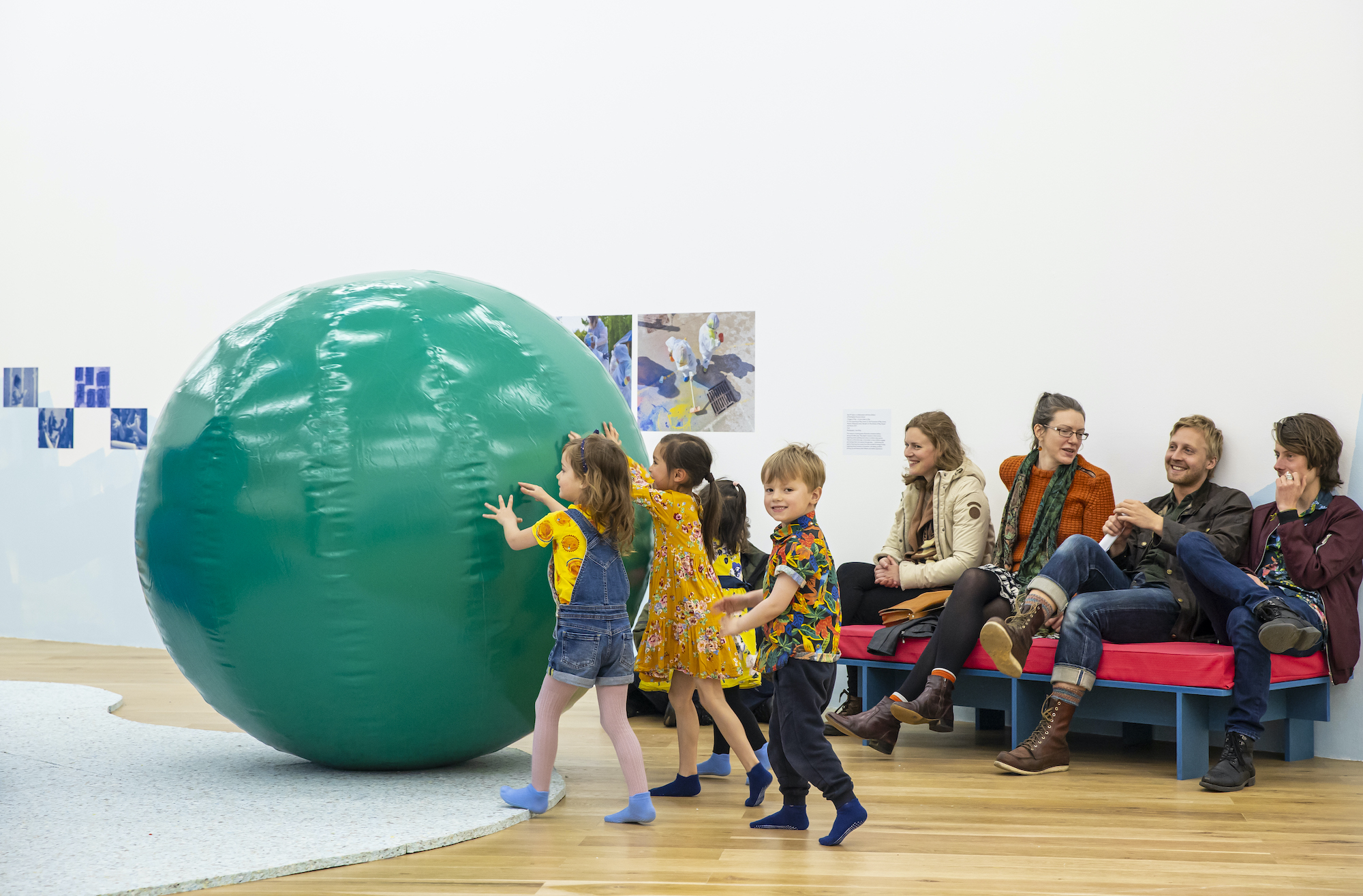 Children push a giant ball in a gallery space