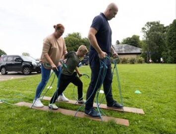 A family walking together on a two planks: as if the planks were skies but all three people all share the same planks. They are holding on to the planks with strings.