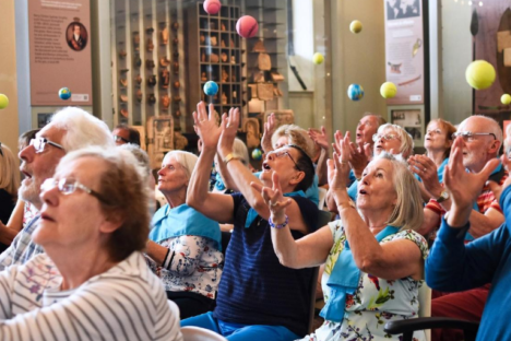 Audience of older visitors preparing to catch different coloured tennis balls